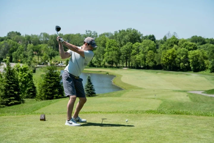 A golfer in a polo shirt and shorts, enjoying time outdoors on a course.