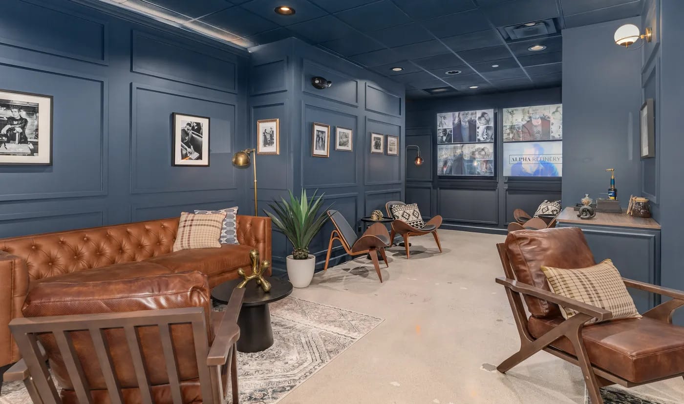 The main lounge at Alpha Refinery, Hinsdale: navy panelled walls, leather seating and framed prints.